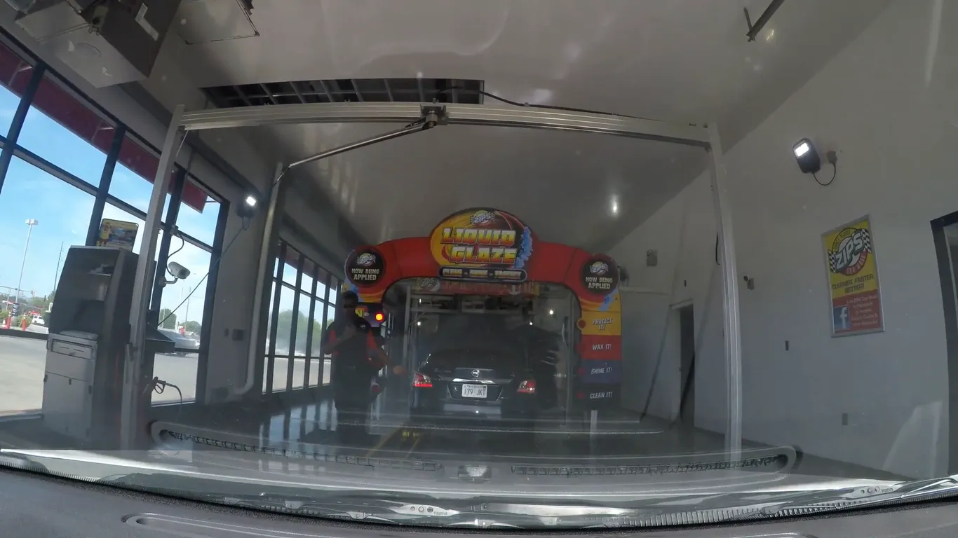 A car waits inside a ZIPS express car wash tunnel in Wichita, Kansas, under a lit arch of brushes